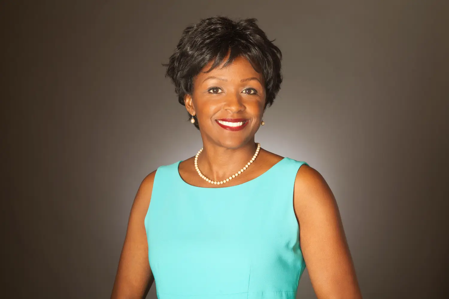 A woman in a blue dress and pearls