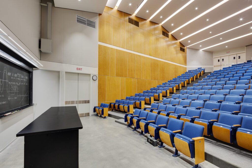 A large auditorium with blue seats and yellow chairs.